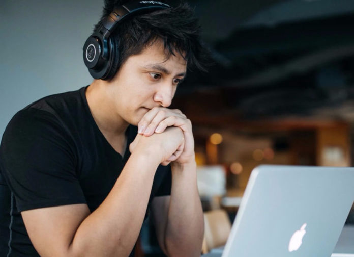 Male student sitting at a laptop computer and wearing headphones