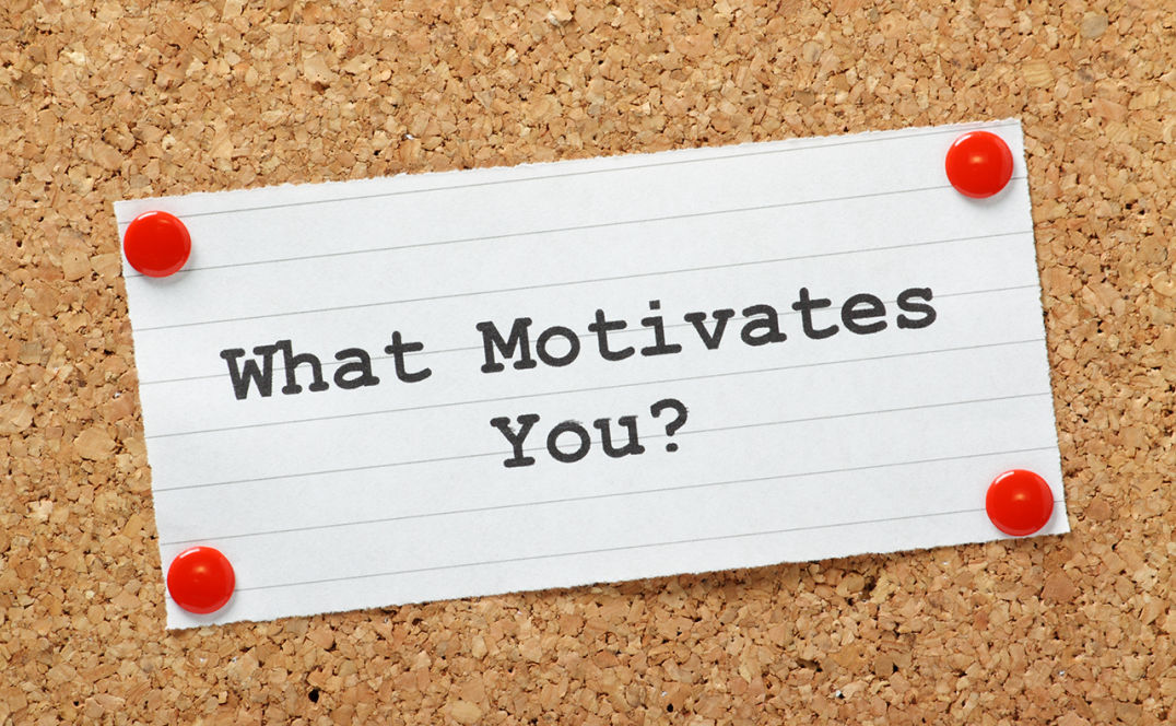 Note thumb-tacked to a cork board that reads, "What Motivates You?"